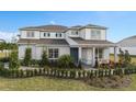 Charming two-story home featuring a manicured lawn, lush landscaping, and inviting front porch seating area at 2141 Weatherly Way, Orlando, FL 32820