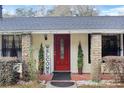 Close-up of the front entrance with a beautiful red door, stone pillars, and manicured greenery at 2525 W Ponkan Rd, Apopka, FL 32712
