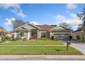 Well-maintained home featuring a lush green lawn, mature trees, and a two-car garage at 3696 Peacepipe Ct, Clermont, FL 34711