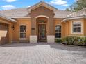 This yellow stucco home offers an elegant entrance with stone accents, a tiled roof and manicured landscaping at 3850 Eagle Isle Cir, Kissimmee, FL 34746