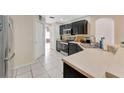 Galley kitchen featuring modern stainless steel appliances, dark cabinetry, tile floors and plenty of counter space at 68 Herring Ct, Kissimmee, FL 34759