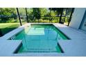 Screened-in, shallow, personal splash pool is surrounded by neutral tile, perfect for lounging at 8991 Cuban Palm Rd, Kissimmee, FL 34747
