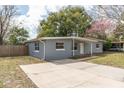 Charming single-story house, showcasing a gray brick exterior, a simple carport, and a spacious concrete driveway at 1205 Flewelling Ave, Ocoee, FL 34761