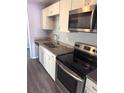 Modern kitchen featuring stainless steel appliances, granite countertops, and white cabinetry at 1219 Dewey Ave, Orlando, FL 32808