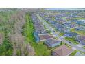 Neighborhood aerial view showing a tree-lined street with sidewalks, well-maintained homes, and a nearby lake at 14031 Jomatt Loop, Winter Garden, FL 34787