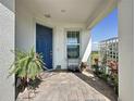 Inviting covered front porch with brick flooring, a blue front door, and decorative plants at 2842 Purple Meadow Ct, Minneola, FL 34715