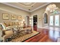 Cozy living room featuring hardwood floors, a tray ceiling, and ample natural light at 3334 Park Grove Ct, Longwood, FL 32779