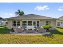 Back exterior view featuring a patio with elegant outdoor seating and lush green lawn at 346 Vista Oaks Way, Davenport, FL 33837