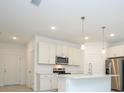 Modern kitchen with white cabinets, stainless steel appliances, and a center island with pendant lighting at 3922 Sw 130Th Loop, Ocala, FL 34473