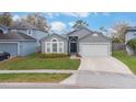 Inviting single-Gathering home with a manicured lawn, gray exterior, and an attached two-car garage at 4909 Fiske Cir, Orlando, FL 32826