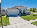 Charming one-story home featuring arched entryway, lush lawn, and attached two-car garage at 5301 Amersham Ln, St Cloud, FL 34771