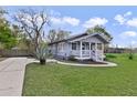 Quaint gray home with a cozy front porch, green lawn and a long driveway at 5990 Hibiscus Rd, Orlando, FL 32807