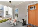 Inviting front porch with rocking chairs, lanterns, and a vibrant orange front door at 936 Allendale Ln, Winter Garden, FL 34787