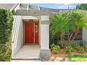 Inviting front entrance with a red door, decorative sidelight, and lush landscaping at 9360 Sonia St, Orlando, FL 32825