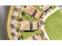 An aerial view of a house with a tile roof, a lush green lawn, and a view of a serene pond at 12016 Lorenza Ln, Orlando, FL 32827