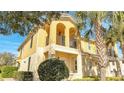 Charming two-story home with a yellow exterior, arched balcony, and lush landscaping at 12016 Lorenza Ln, Orlando, FL 32827