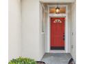 Close-up of a vibrant red front door with decorative glass and modern hardware, offering a welcoming entrance at 1601 Stoneywood Way, Apopka, FL 32712