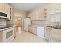 Cozy kitchen with light wood cabinets, white appliances and a view of the dining room at 1601 Stoneywood Way, Apopka, FL 32712