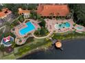 Aerial view of a community pool area with multiple pools, lounge chairs, and lush landscaping near a lake at 3018 Red Ginger Rd, Kissimmee, FL 34747