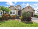 Beautiful two-story home featuring a manicured lawn and colorful landscaping at 4414 Azure Isle Way, Kissimmee, FL 34744