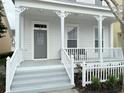 Inviting front porch with classic white columns, a gray front door and a well-maintained yard at 802 Rosa St, Celebration, FL 34747