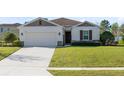 Charming single-story home with a well-manicured lawn and attached two-car garage at 1727 Garden View St, Mascotte, FL 34753