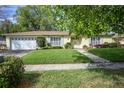 Lovely single-story home with a lush green lawn and beautiful, mature trees at 3030 Kingfisher Dr, Orlando, FL 32806