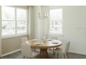 Bright dining room featuring a wooden table, four chairs, large windows with white trim and sheer curtains, and modern chandelier at 3489 Salvia Ct, Tavares, FL 32778