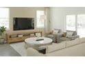 Bright living room with large windows, sofa and chairs, TV, wooden cabinet, and a marble coffee table on top of a rug at 3489 Salvia Ct, Tavares, FL 32778