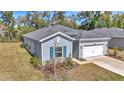 Side view of a blue single-Gathering home with a well-maintained lawn, shuttered windows, and a two-car garage at 7651 Sw 74Th Loop, Ocala, FL 34481