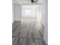 Sun-filled living room featuring new gray wood flooring and a ceiling fan at 11618 Churchill St, Orlando, FL 32817
