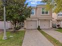 Inviting townhome showcasing a brick driveway, well-manicured lawn, and two-car garage at 1206 Bella Cara Ct, Davenport, FL 33896