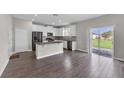 Open concept kitchen with white cabinetry, gray countertops, stainless appliances, and wood-look floors at 1616 Oak Blossom Dr, Davenport, FL 33837