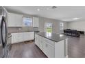 Open concept kitchen with island, white cabinets, grey countertops, stainless appliances, and wood-look floors at 1616 Oak Blossom Dr, Davenport, FL 33837