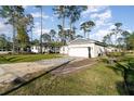 A single-story home with a paved driveway and two-car garage amidst a lush, treed lawn at 1959 9Th Ave, Deland, FL 32724