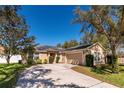 Inviting home with a spacious driveway, lush landscaping, and solar panels for energy efficiency at 2005 Blackbird Dr, Apopka, FL 32703