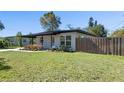 Side angle of the home with manicured lawn, a covered patio, and a charming privacy fence at 212 Oakland Ave, Sanford, FL 32773