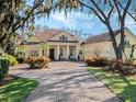 Beautiful home featuring a circular driveway, pillars at the front door, and a landscaped front yard with blue skies at 10411 Hart Branch Cir, Orlando, FL 32832