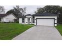 Charming new home with a white exterior, black trim, concrete driveway and a fresh green lawn at 12793 Sw 43Rd Cir, Ocala, FL 34473
