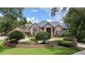 Elegant brick home with lush front yard landscaping, brick retaining wall, and large trees at 1500 Whitstable Ct, Lake Mary, FL 32746