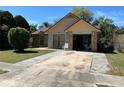 Inviting home exterior with a well-manicured lawn, mature trees, and attached garage at 1663 Sunburst Way, Kissimmee, FL 34744