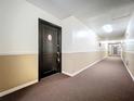 Long hallway with neutral colors, and brown carpet leading to a black door to unit E-1 at 1695 Lee Rd # E205, Winter Park, FL 32789