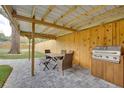 Outdoor dining area with a grill, table, and chairs on a stone patio under a beautiful pergola at 224 E Kelly Park Rd, Apopka, FL 32712