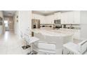 Open kitchen featuring marble counters, white cabinets, stainless steel appliances and seating at the island at 280 Burma St, Kissimmee, FL 34747