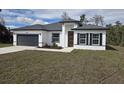 Charming home featuring a gray roof, gray garage door, modern front door, and a well-manicured lawn at 3519 Sw 131St Place St, Ocala, FL 34473