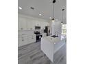 Bright kitchen boasts quartz counters, stainless appliances, a large island and stylish gray wood-look floors at 3519 Sw 131St Place St, Ocala, FL 34473