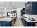 Modern kitchen boasts sleek blue cabinetry, a large island, stainless steel appliances, and light wood flooring at 6117 Sandy Springs Ct, St Cloud, FL 34771