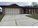 Charming single-story home with a two car garage and well-maintained landscaping and a cracked driveway at 6567 Magee Ct, Orlando, FL 32818