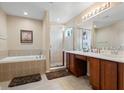 Elegant bathroom boasts double sinks, a glass-enclosed shower, and a relaxing soaking tub at 901 Dorset Pl, Davenport, FL 33896