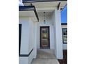 A modern front door design with clear glass and a sleek, dark frame against a stucco wall at 15462 Sw 46 Cir, Ocala, FL 34473